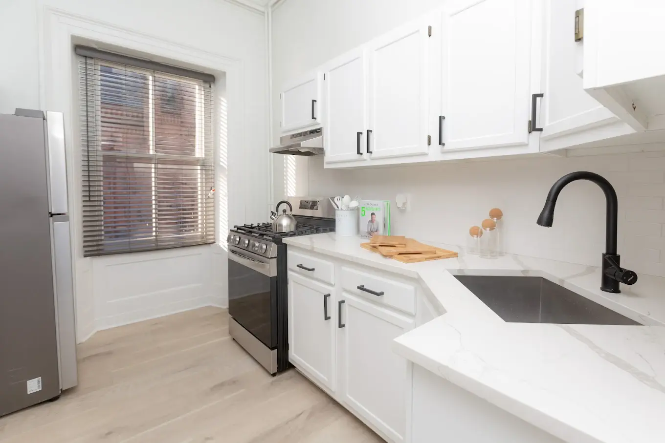 A kitchen with white cabinets and a black faucet.